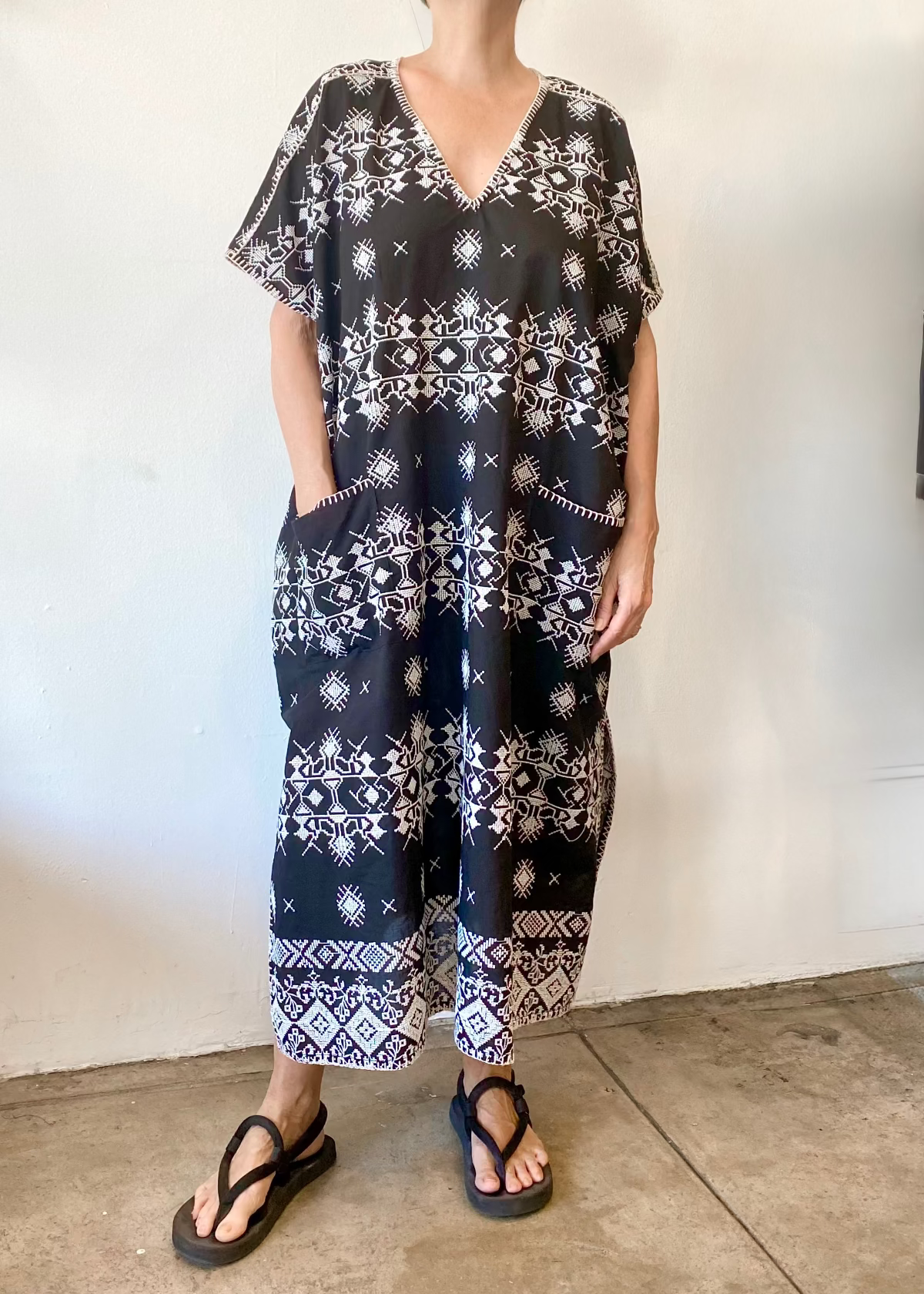 v-neck black caftan to ankles, hand in pocket