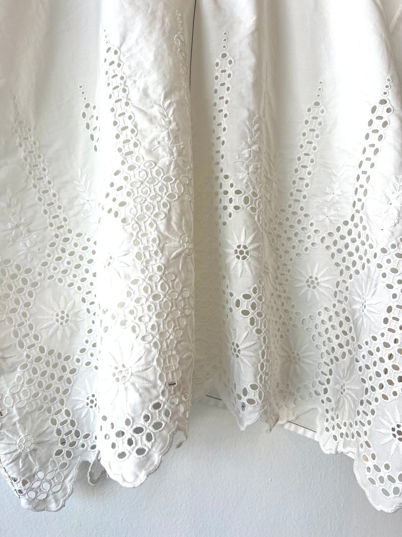 white shirt with eyelet and white embroidery against a white wall