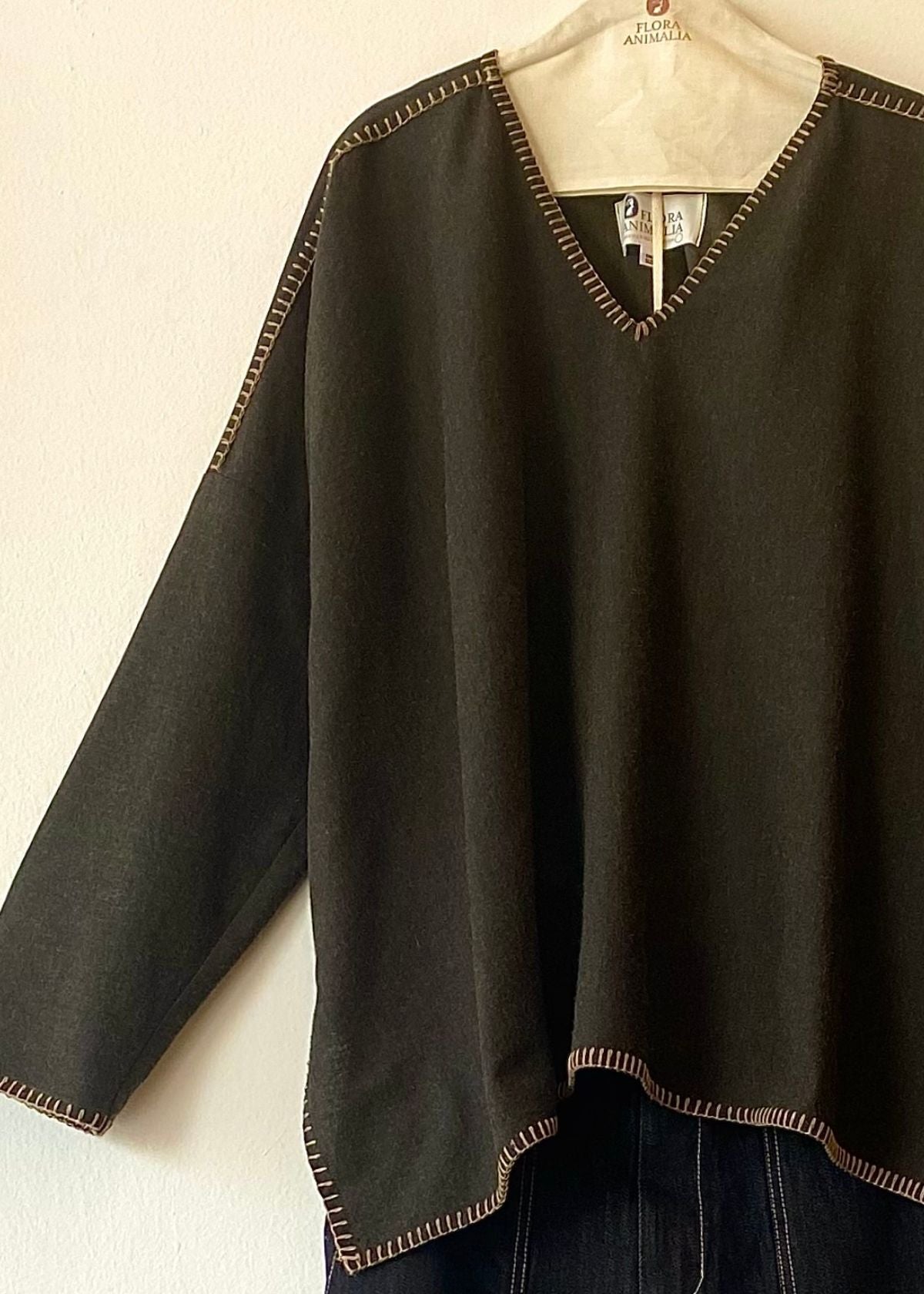 dark green v-neck Praia top with tan trim on a hanger against a white background