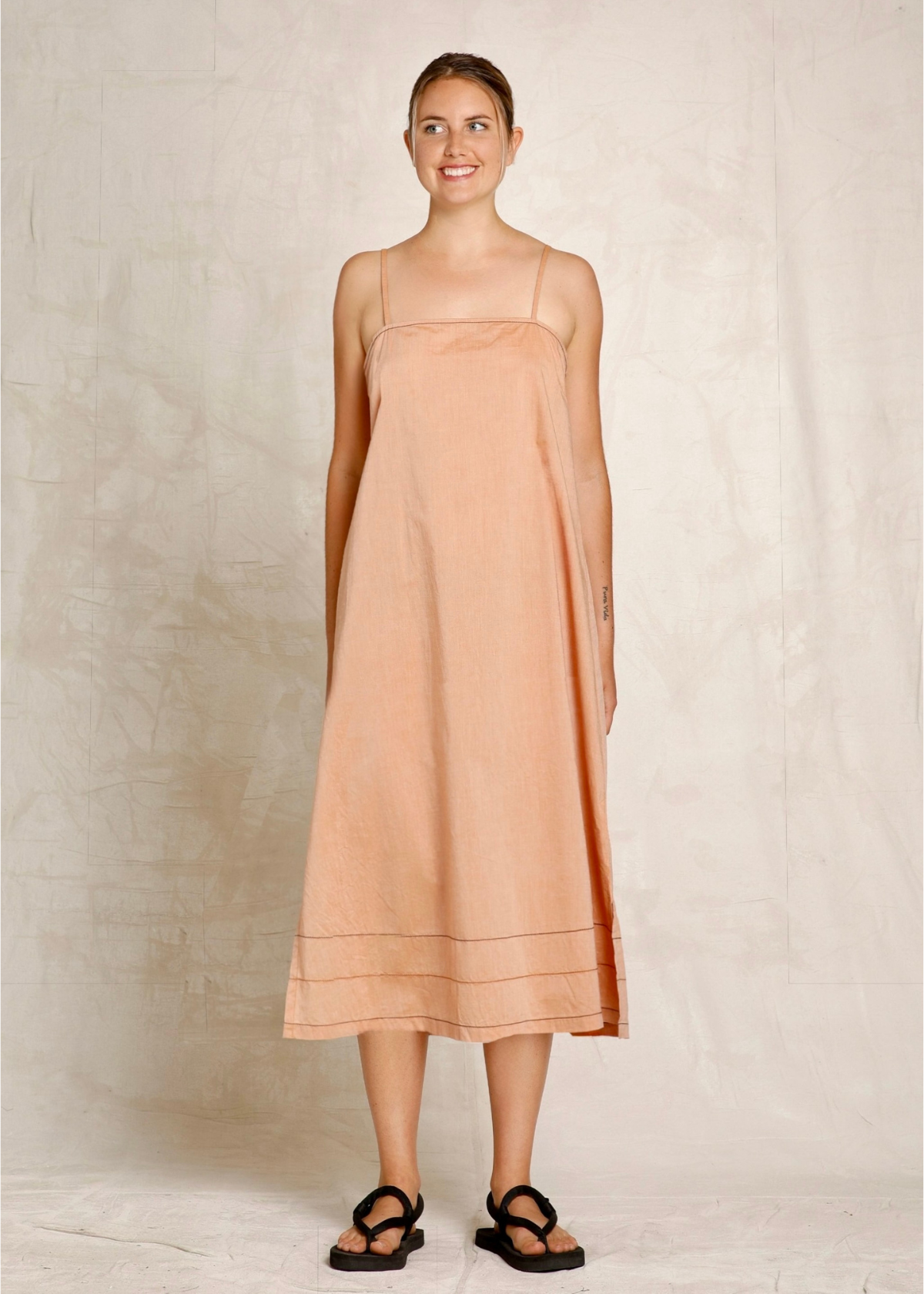 Woman wearing a peach dress against a plain background