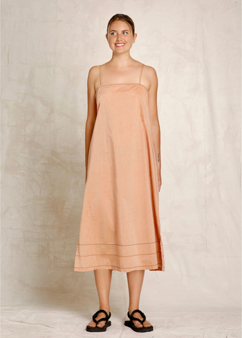 Woman wearing a peach dress against a plain background