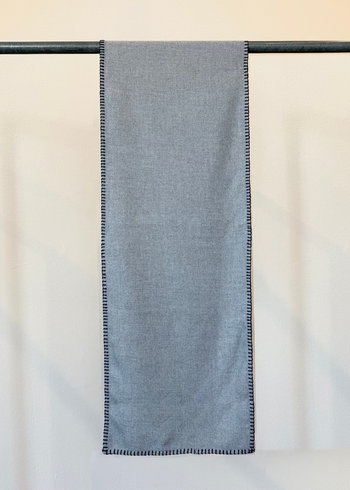 Everyday Scarf in Ash Gray Plant based flannel with blanket edge stitch hanging flat from a pole against a plain background.