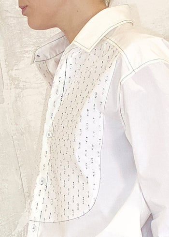 Close-up of a white shirt with silver metallic dots on a neutral background