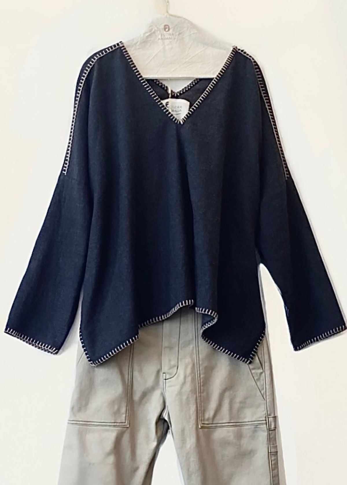 Navy blue v-neck Praia top with tan trim on a hanger against a white background