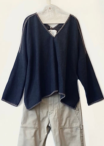 Navy blue v-neck Praia top with tan trim on a hanger against a white background