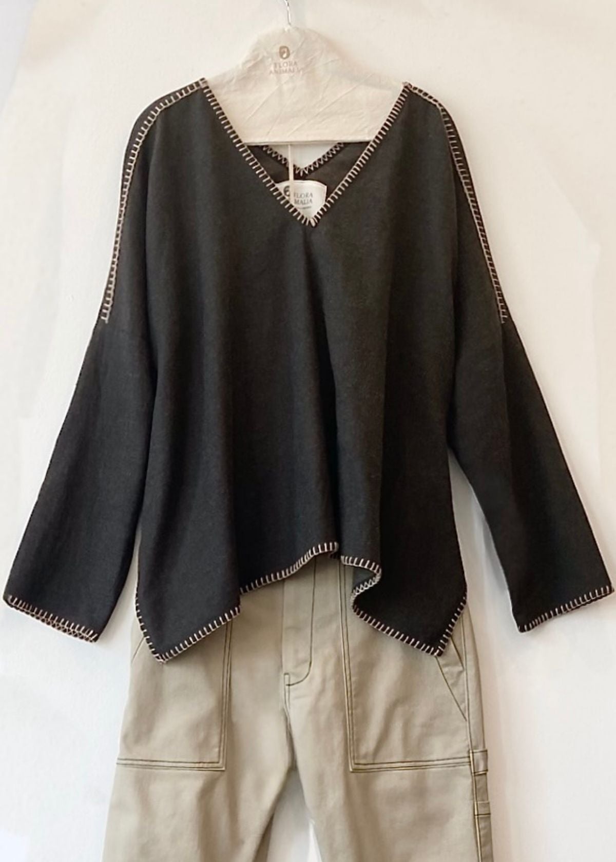 Navy blue v-neck Praia top with tan trim on a hanger against a white background