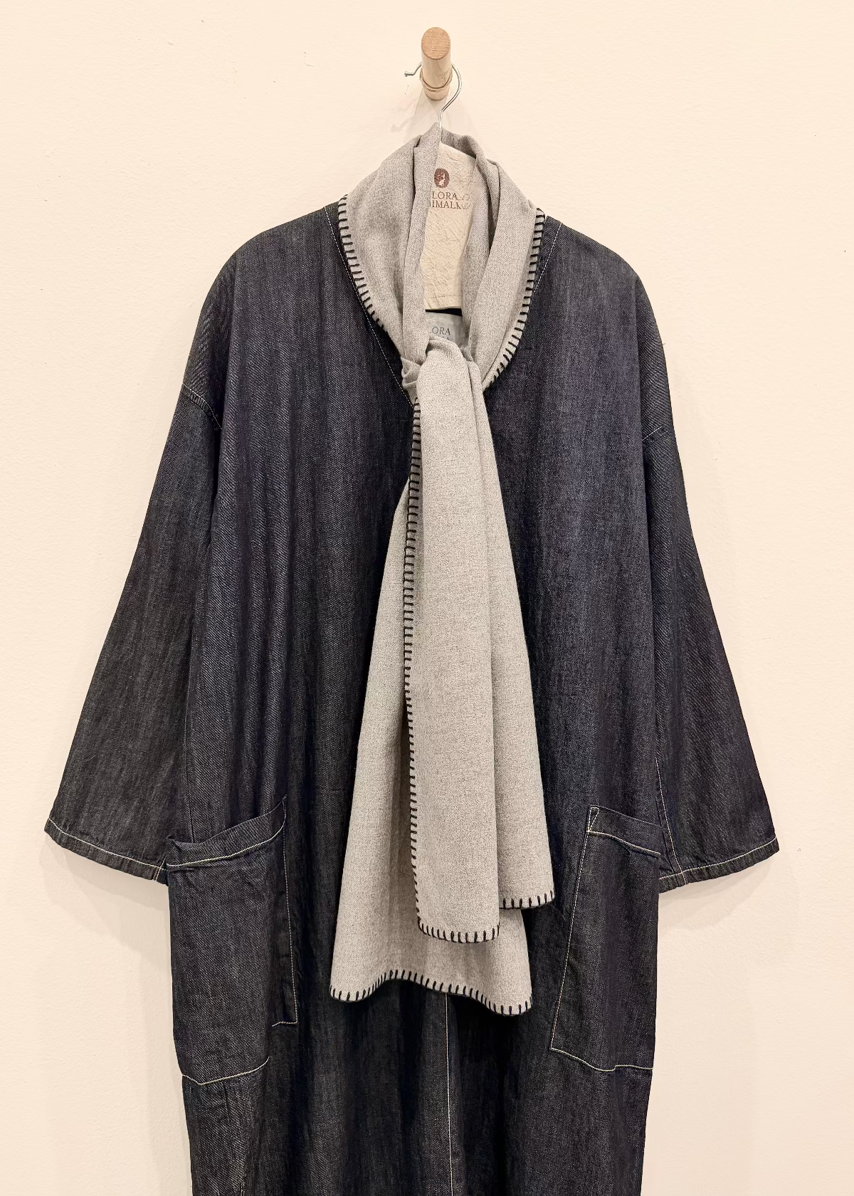 Everyday Scarf in Ash Gray Plant based flannel with blanket edge stitch hanging from a pole against a plain background.