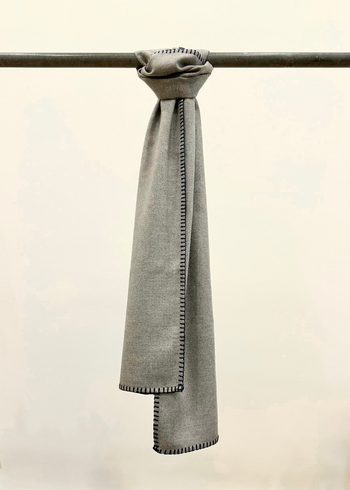 Everyday Scarf in Ash Gray Plant based flannel with blanket edge stitch hanging from a pole against a plain background.