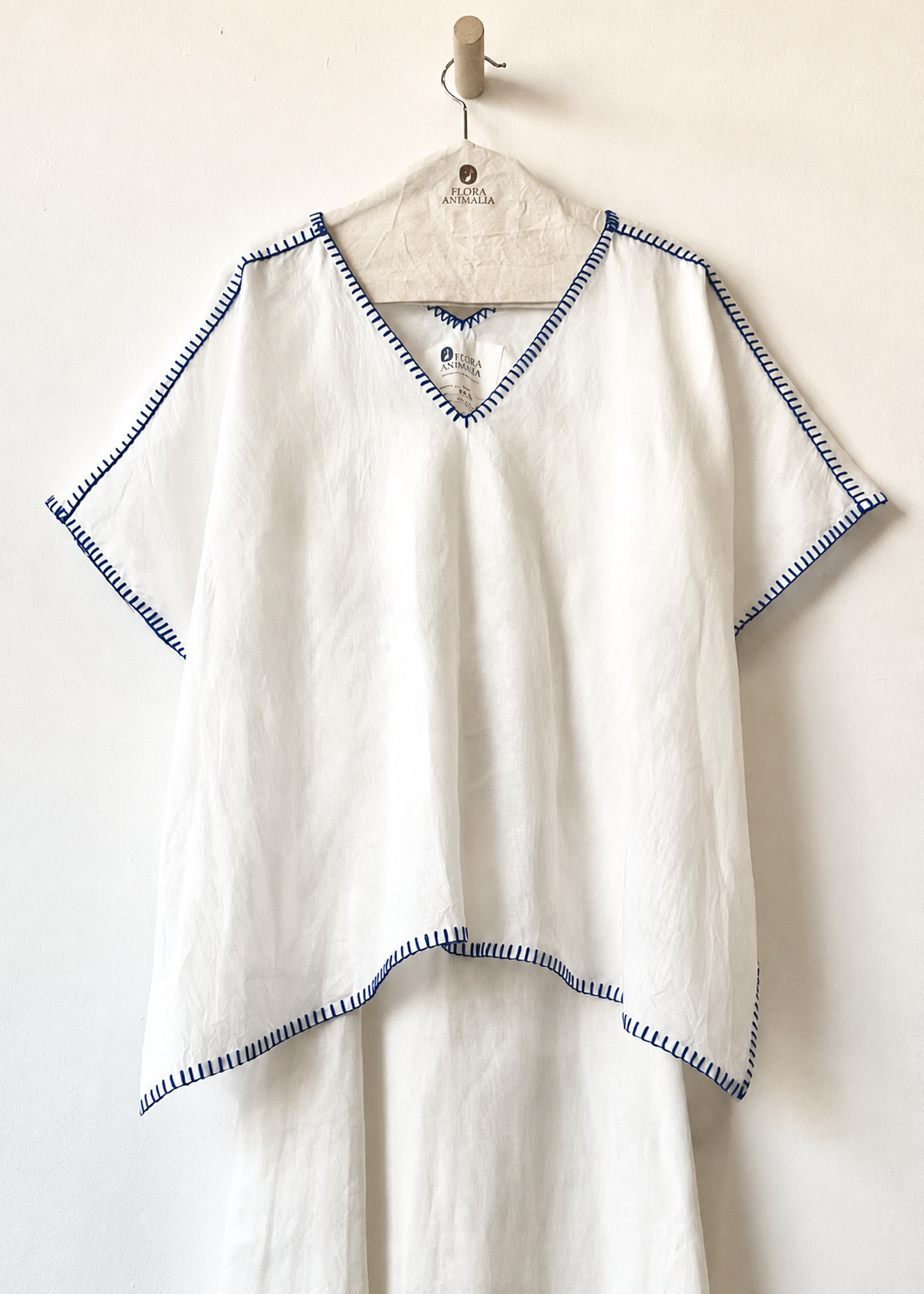 Brown poncho with blue trim on a hanger against a white background