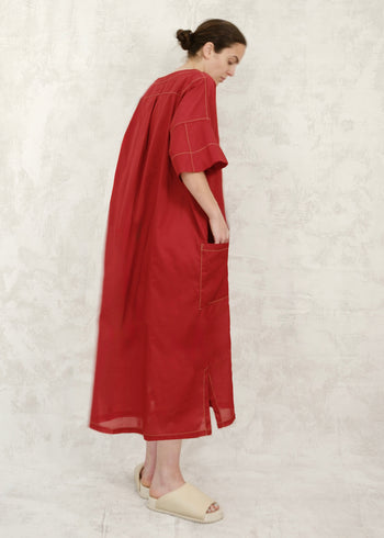 Woman wearing a red dress against a light textured wall