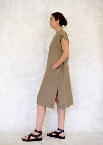 model in khaki colored linen sheath dress with hand in pocket side view