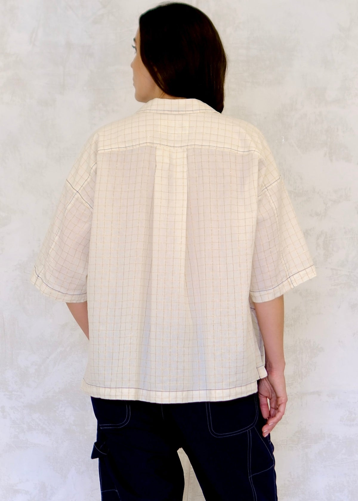 back view of Person wearing a light-colored textured shirt against a white background