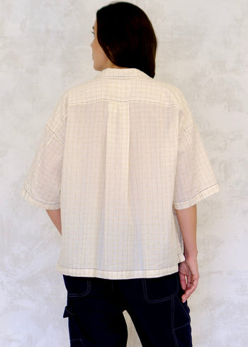 back view of Person wearing a light-colored textured shirt against a white background