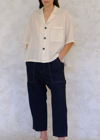 Person wearing a light-colored shirt and dark pants against a white background