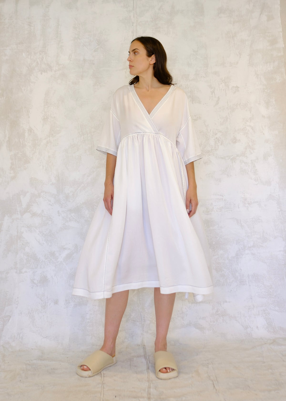 Woman wearing a white dress against a textured white background
