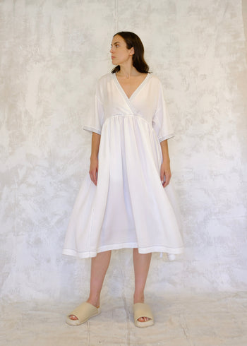 Woman wearing a white dress against a textured white background