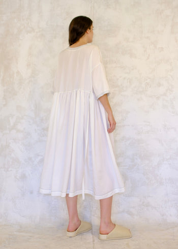 Rear view, Person wearing a white dress against a textured white background