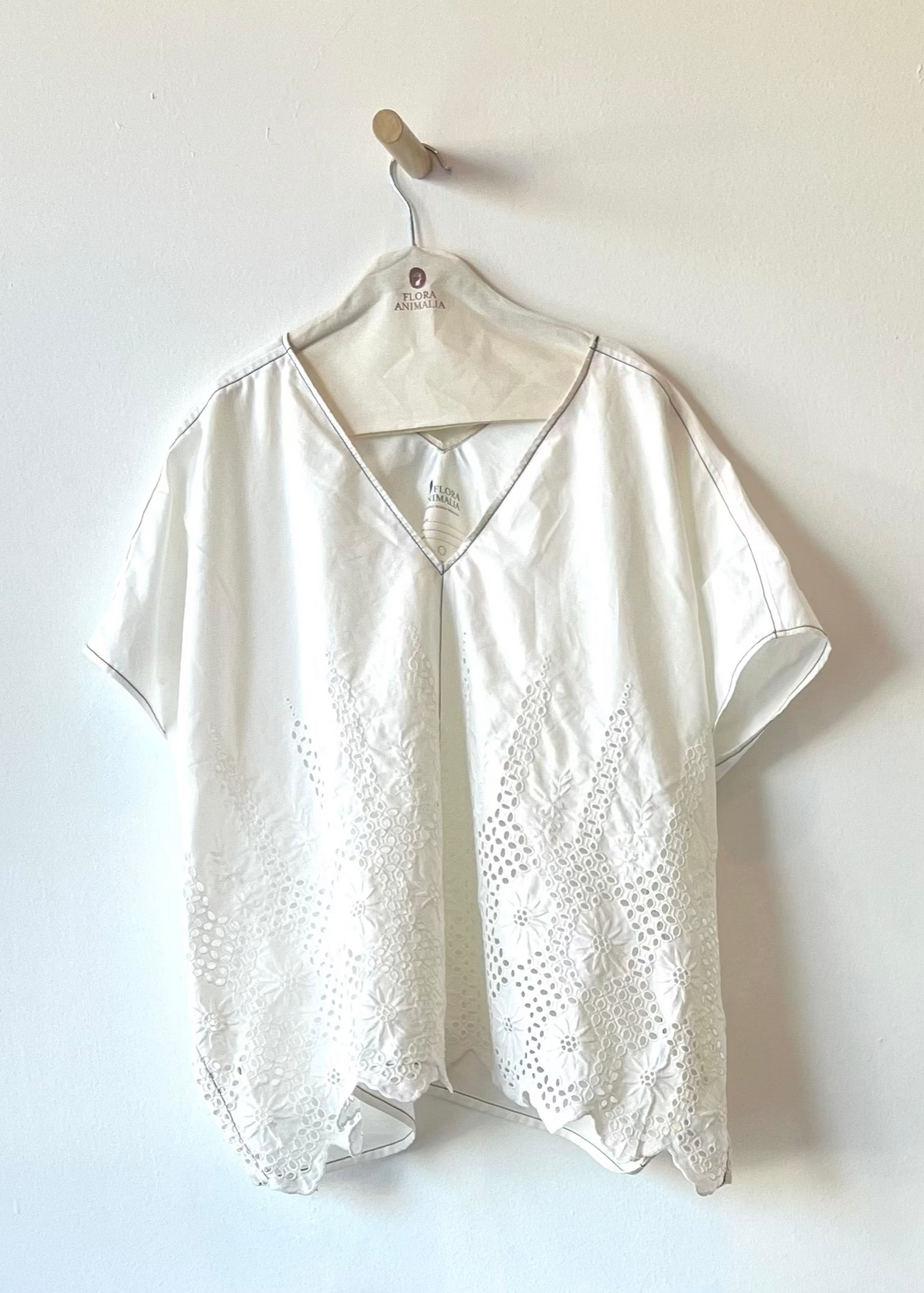 white shirt with eyelet and white embroidery against a white wall