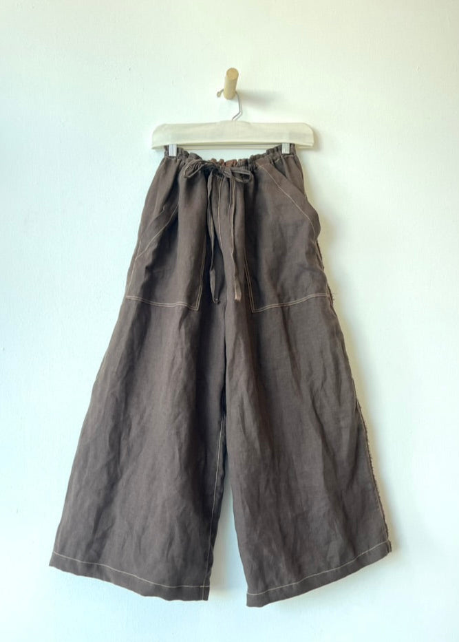 brown drawstring pants hanging against a white wall