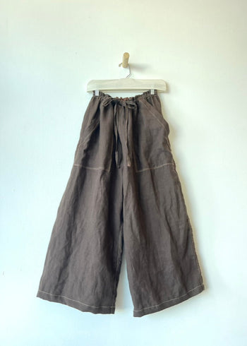 brown drawstring pants with patch pockets hanging against a neutral all