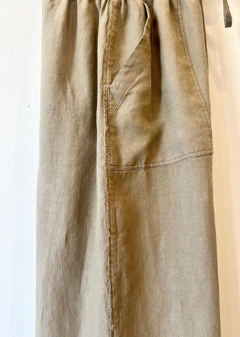 side detail of Beige pants with pocket and frayed edge on a white background