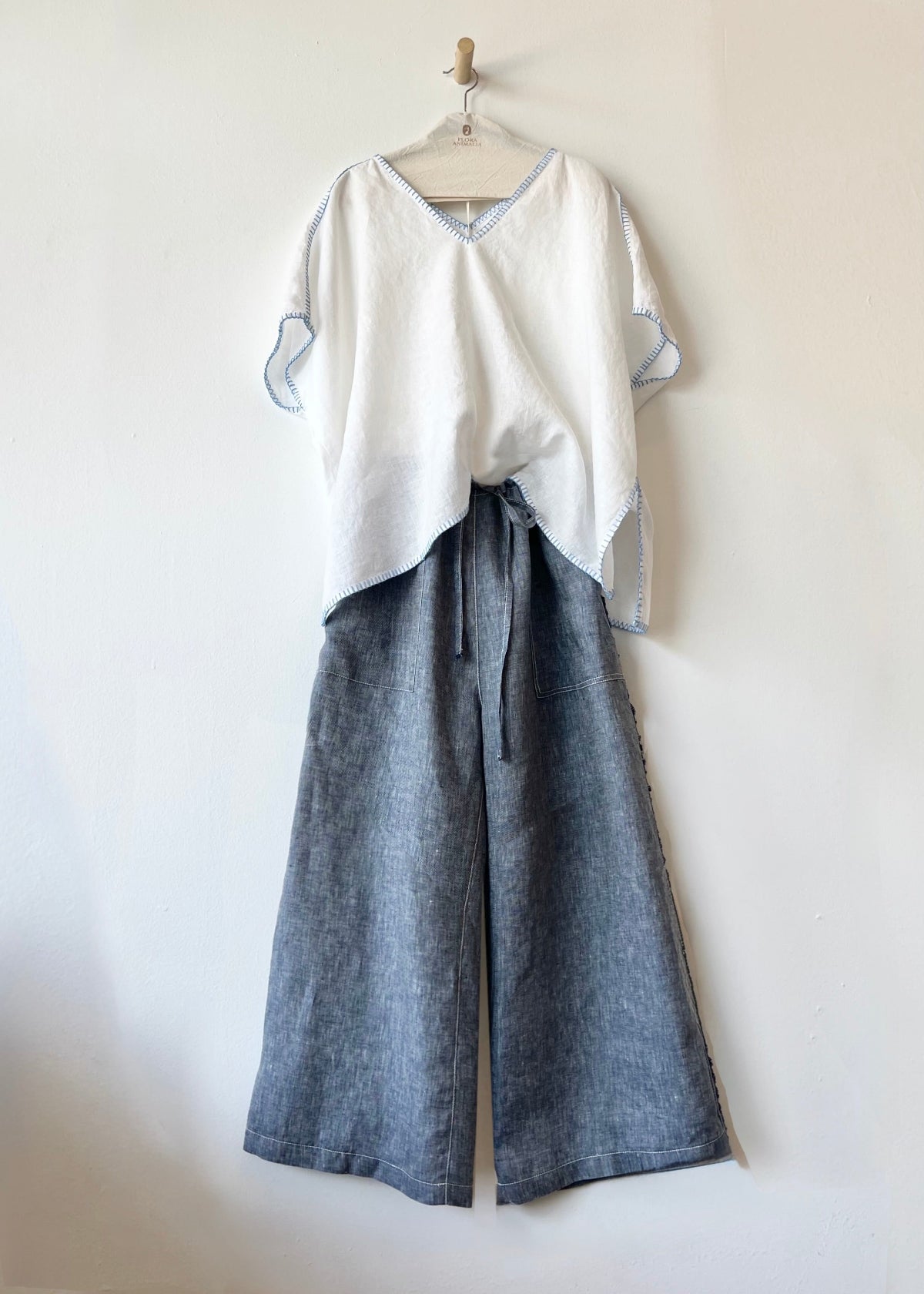 White top and blue-gray wide-leg pants on a hanger against a white background
