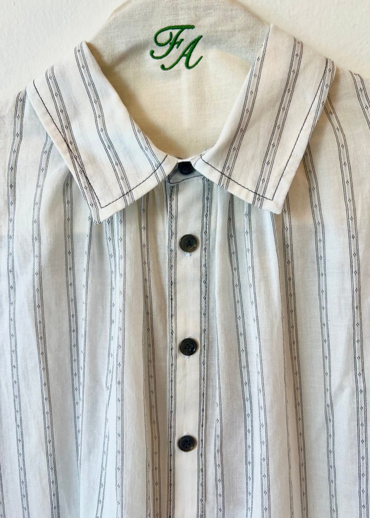 white shirt with black stripes collar with buttons on a hanger with brand initials FA 