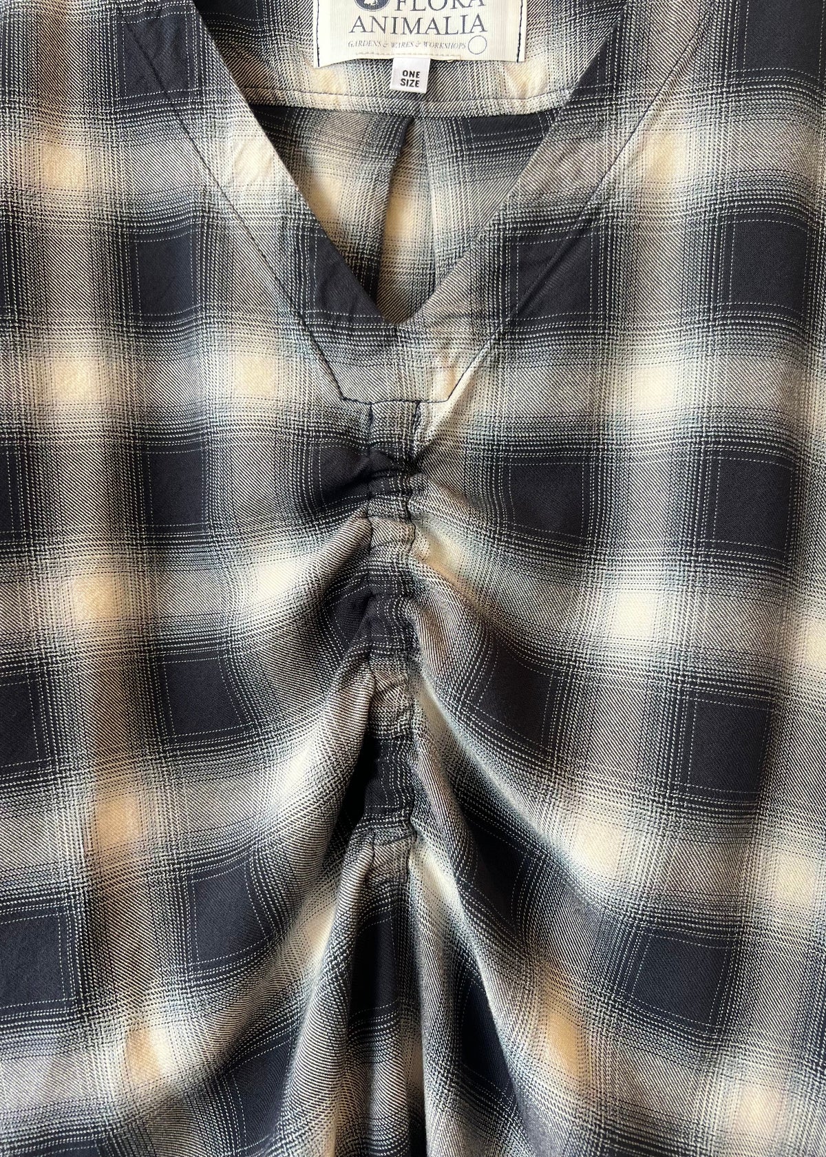 Close-up of a plaid v-neck shirt with a brand label visible