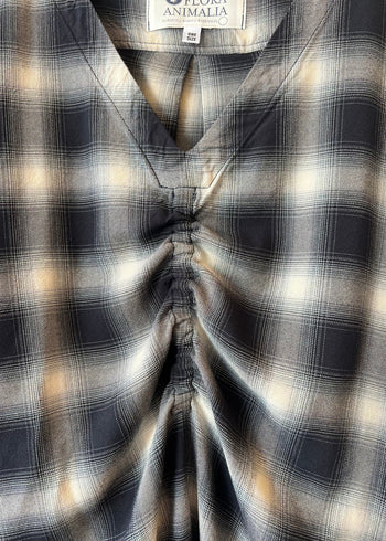 Close-up of a plaid v-neck shirt with a brand label visible