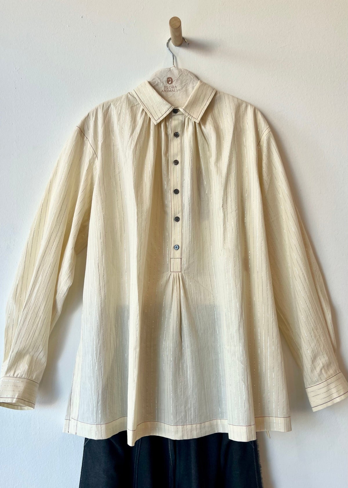 off white button down top hanging against neutral wall