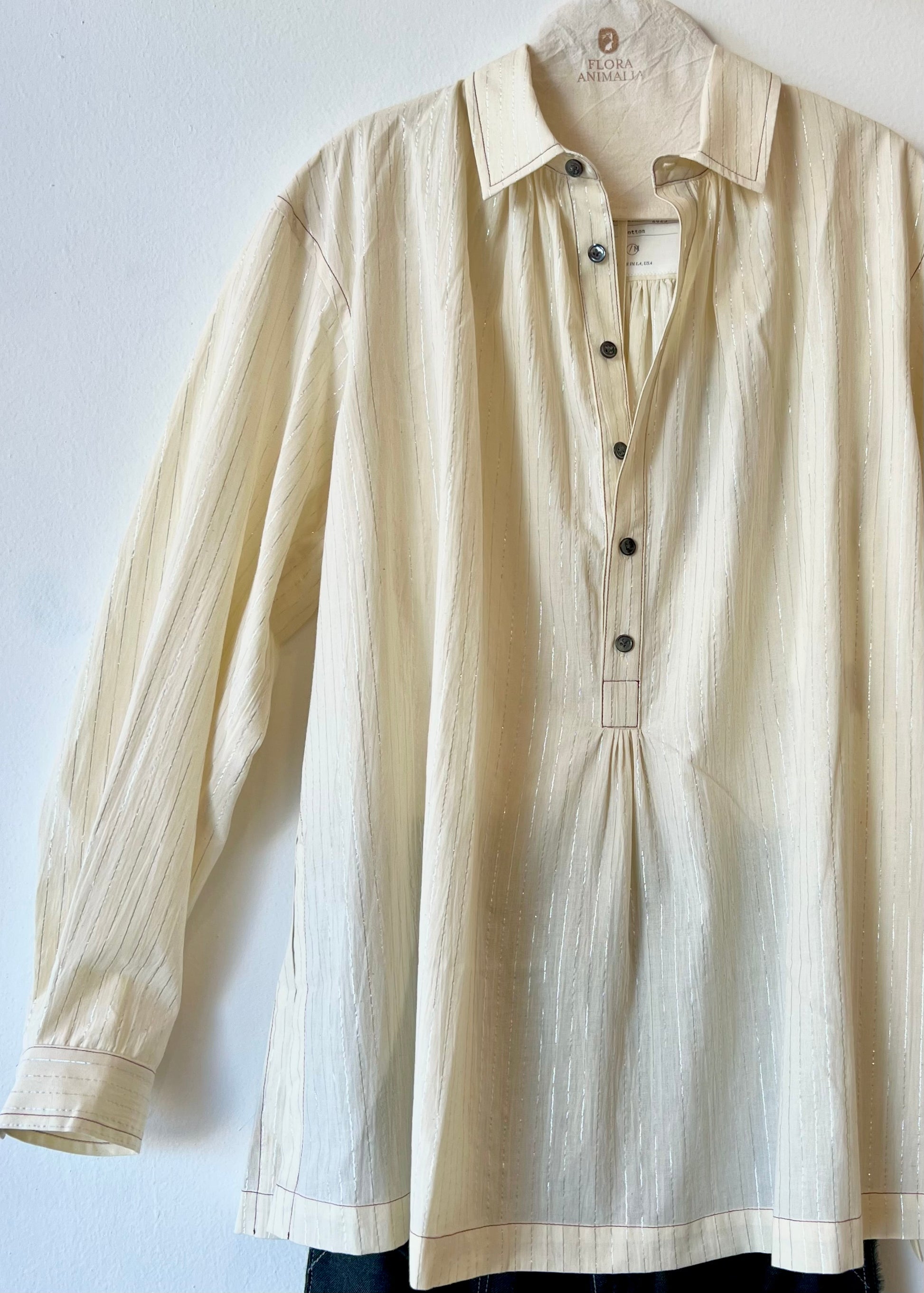 Beige and silver striped shirt on a hanger against a light background