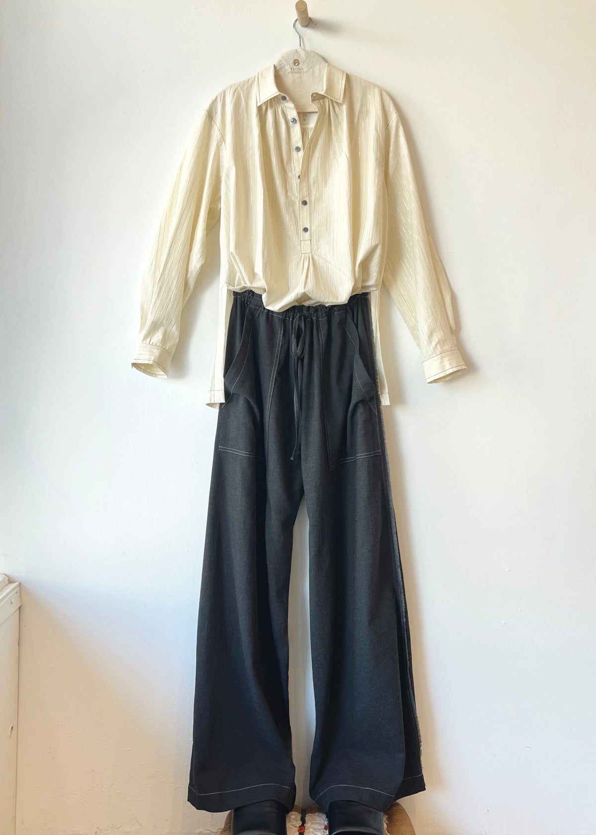 off white button shirt and long gray pants against a white wall