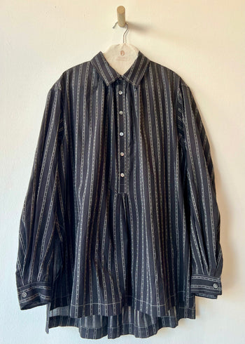 black long sleeve shirt with collar hanging against a gray wall
