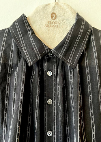 collar closeup of black shirt with white stripes on a hanger with flora animalia logo