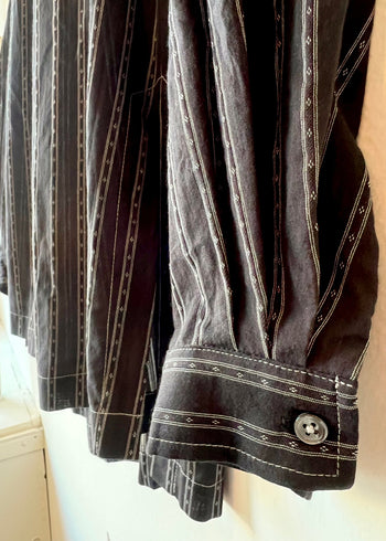 closeup of black shirt with white stripes sleeve cuff  and hem