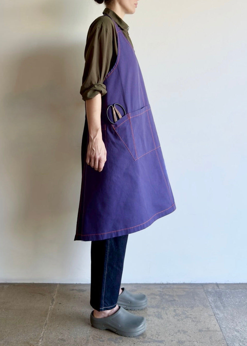 Model wearing Flora Animalia organic canvas harvest apron in purple grape, side view.