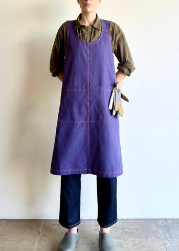 Model wearing Flora Animalia organic canvas harvest apron in purple grape, front.