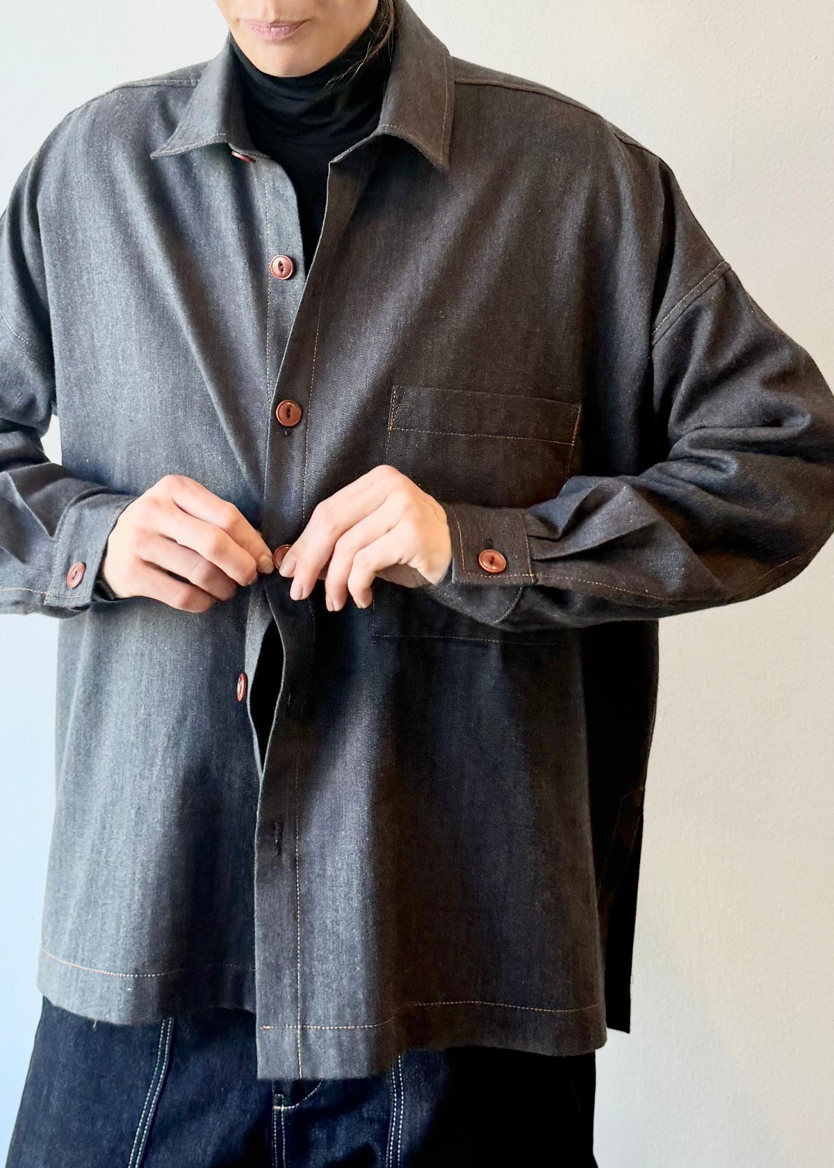 Person wearing a dark blue button shirt with on a plain background