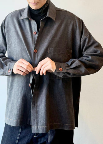 Person wearing a dark blue button shirt with on a plain background