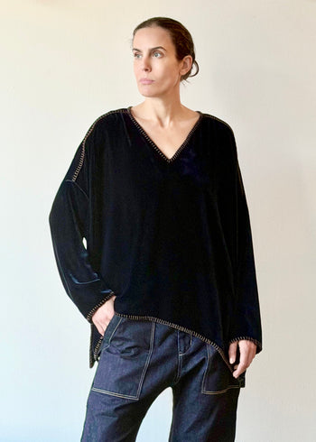 Model wearing a navy blue velvet Praia tunic with long sleeves and a V-neckline against a plain background.
