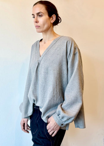 Woman wearing a light gray flannel v-neck against a plain background