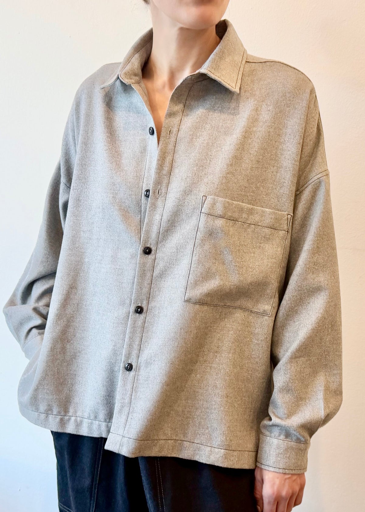 Person wearing a blue flannel shirt with brown buttons and one pocket with dark drawstring picker's  pants on a gradient background