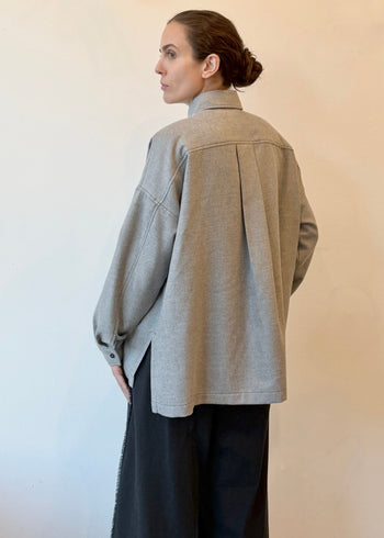 Rear view of person wearing a light gray flannel top with a plain background