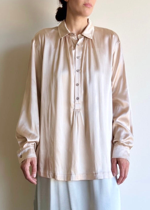 Woman wearing a beige blouse against a plain background