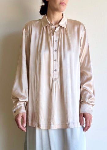 Woman wearing a beige blouse against a plain background