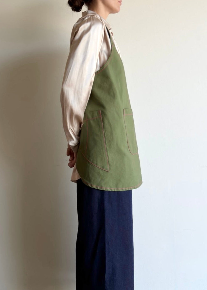 Side view of Person wearing a green apron and navy pants showing utility pockets.