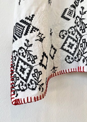 white embroidered tunic with red blanket stitching hem detail