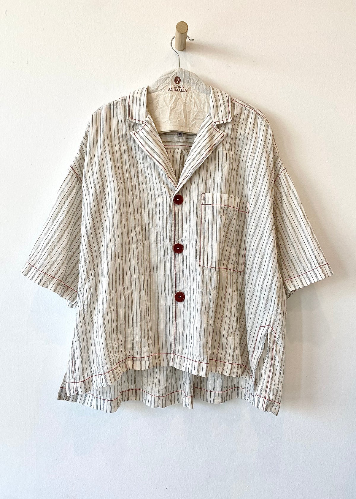 Woman wearing a cream checkered shirt with black buttons on a light gray background