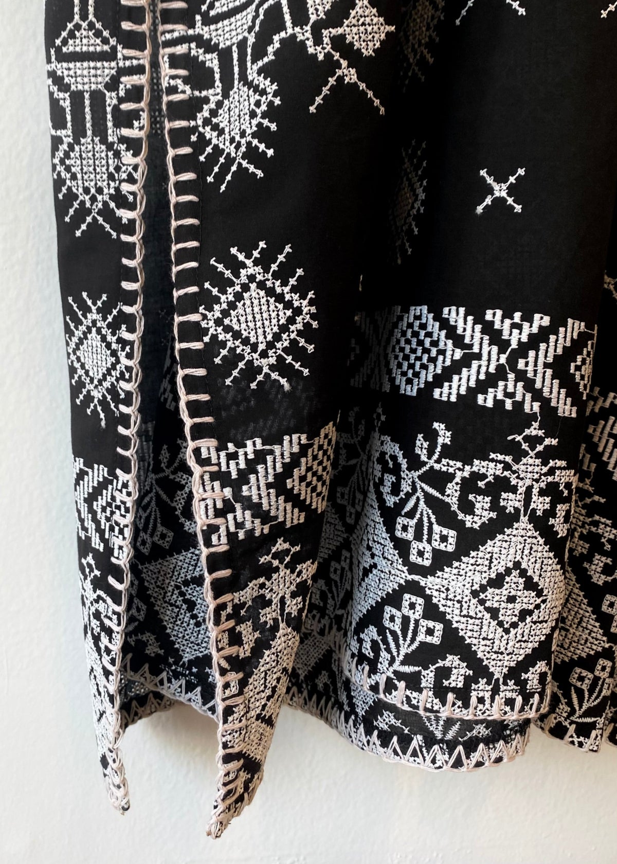 Hem ofblack caftan with white embroidery blanket stitch detail