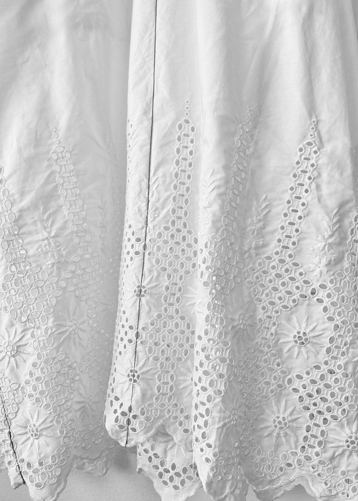 White dress with eyelet details on a hanger against a white background
